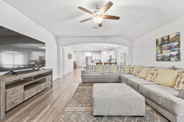 living room featuring wood-type flooring, ceiling fan, and vaulted ceiling