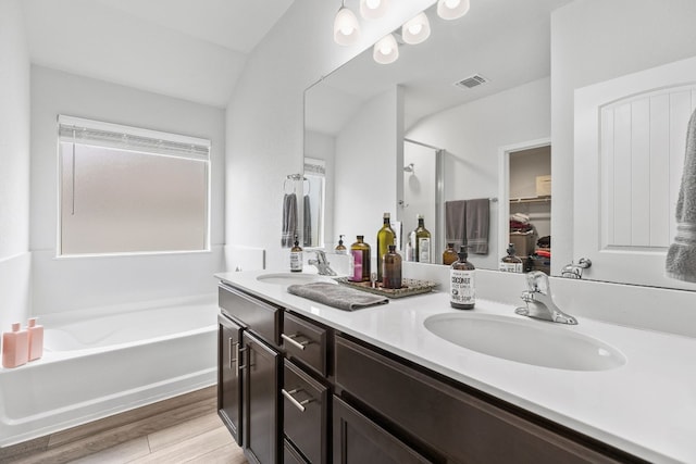 bathroom with independent shower and bath, vanity, vaulted ceiling, and hardwood / wood-style floors