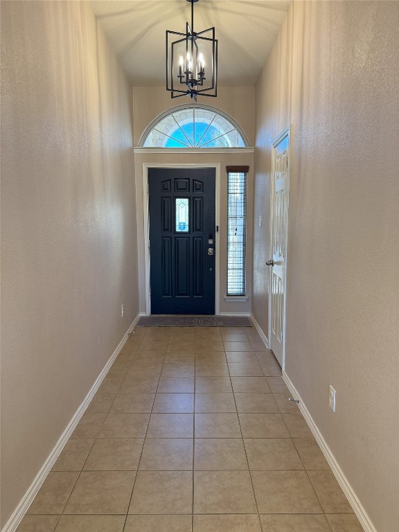 tiled entryway featuring an inviting chandelier