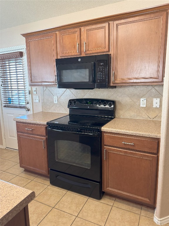 kitchen with light tile patterned flooring, tasteful backsplash, and black appliances