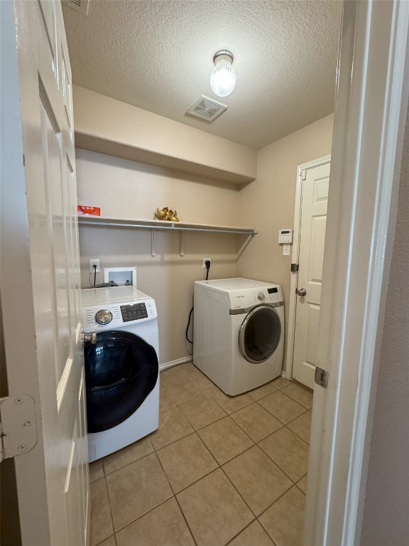 laundry area featuring light tile patterned flooring, independent washer and dryer, and a textured ceiling