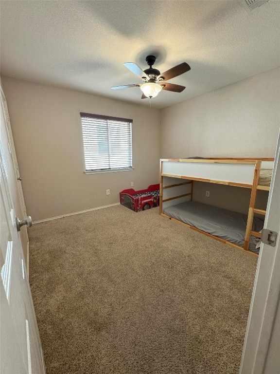 unfurnished bedroom with ceiling fan, carpet flooring, and a textured ceiling