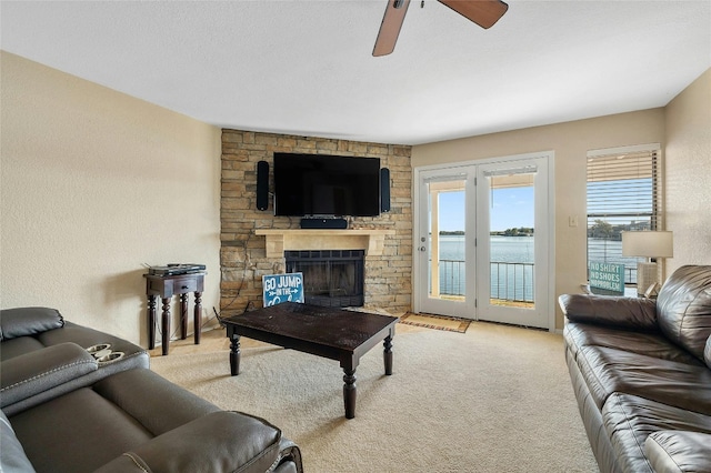 carpeted living area featuring ceiling fan and a stone fireplace