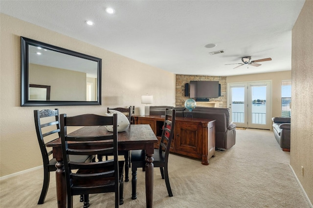 carpeted dining space with visible vents, ceiling fan, a textured wall, and baseboards