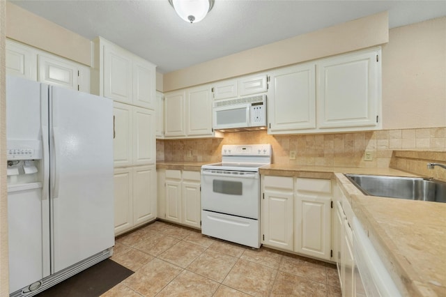 kitchen featuring tasteful backsplash, white appliances, light countertops, and a sink