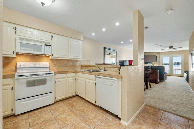 kitchen featuring white appliances, decorative backsplash, ceiling fan, a sink, and open floor plan