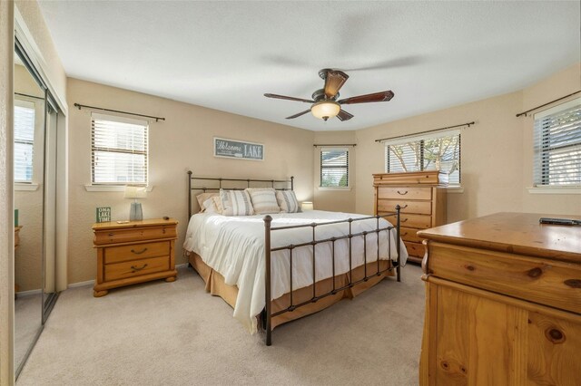 bedroom featuring a ceiling fan, a closet, and light carpet
