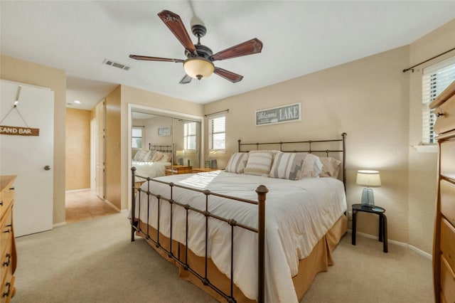 bedroom featuring light colored carpet, visible vents, a closet, baseboards, and a ceiling fan