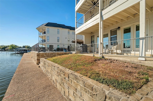surrounding community with a patio area, a water view, and a boat dock