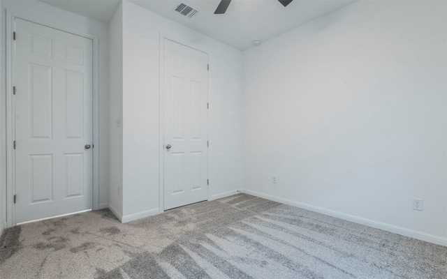 unfurnished bedroom with ceiling fan, carpet, visible vents, and baseboards