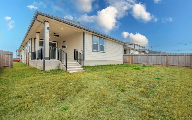 back of property featuring ceiling fan, a lawn, and fence