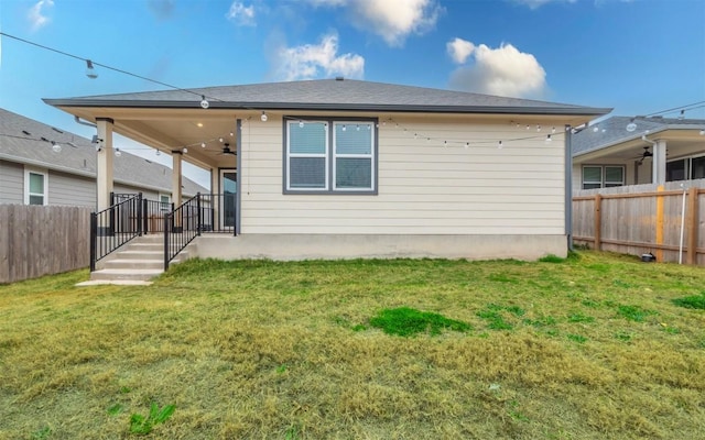 rear view of property with a yard, fence private yard, and a ceiling fan