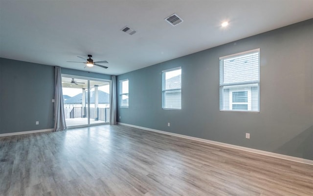 unfurnished room featuring visible vents, ceiling fan, baseboards, and wood finished floors