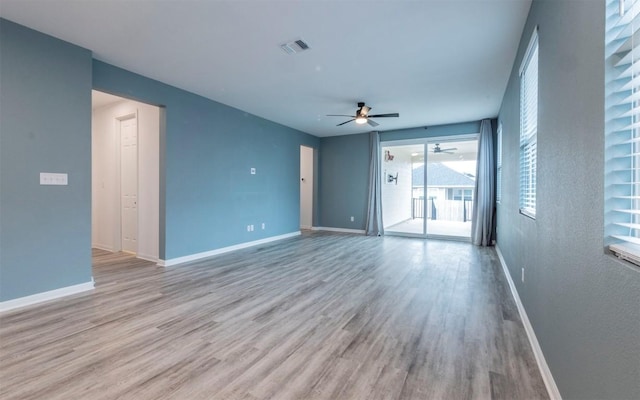 unfurnished room featuring a ceiling fan, visible vents, baseboards, and wood finished floors