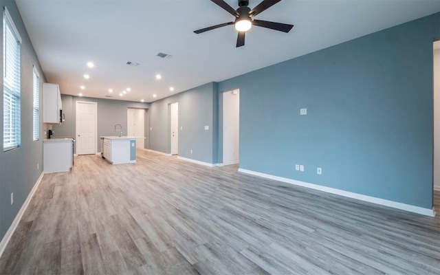 unfurnished living room featuring ceiling fan, light wood-type flooring, visible vents, and baseboards