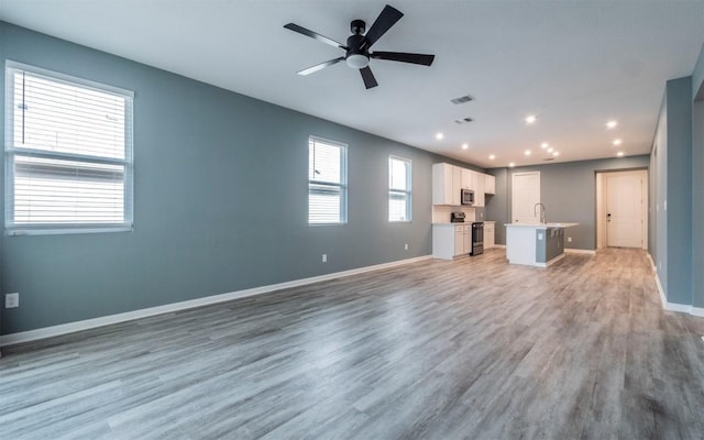 unfurnished living room with ceiling fan, recessed lighting, light wood-style flooring, and baseboards