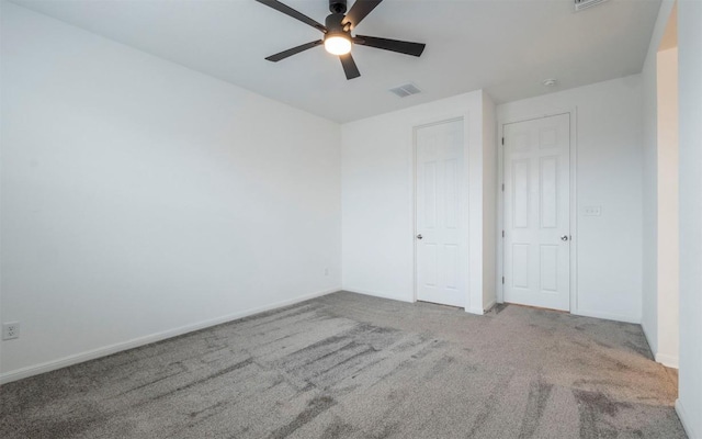 empty room with carpet floors, baseboards, visible vents, and ceiling fan