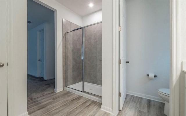 full bathroom featuring wood finished floors, a shower stall, toilet, and baseboards