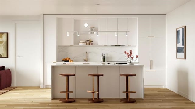 bar featuring sink, light wood-type flooring, white cabinets, and backsplash