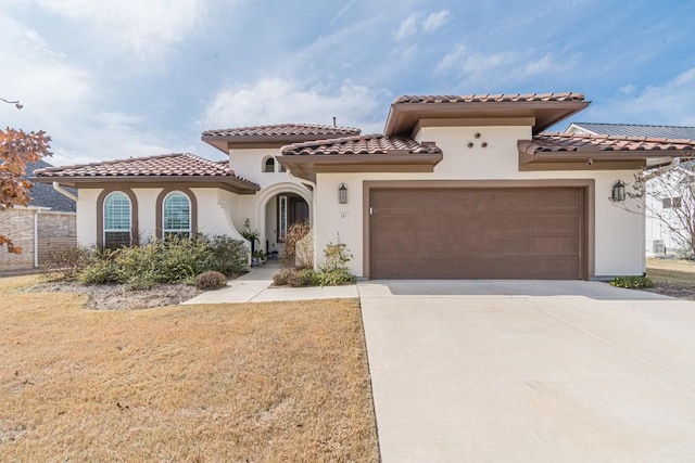 mediterranean / spanish home featuring a garage and a front yard