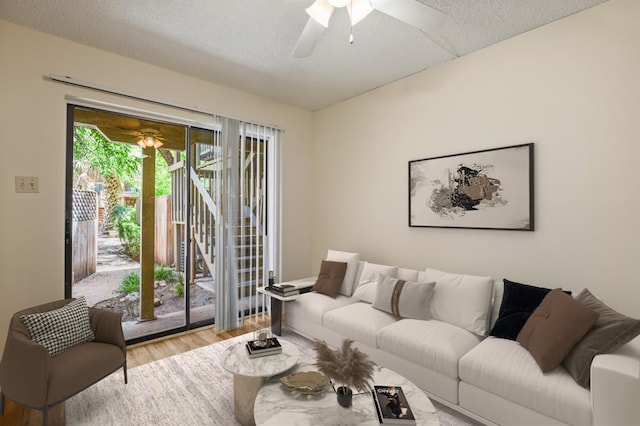 living room featuring ceiling fan, light hardwood / wood-style floors, and a textured ceiling