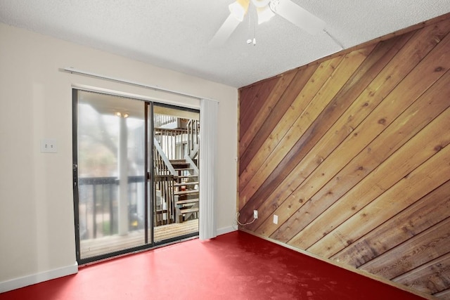 spare room featuring ceiling fan, wooden walls, and a textured ceiling