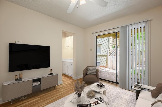 living room featuring a textured ceiling, light hardwood / wood-style flooring, and ceiling fan