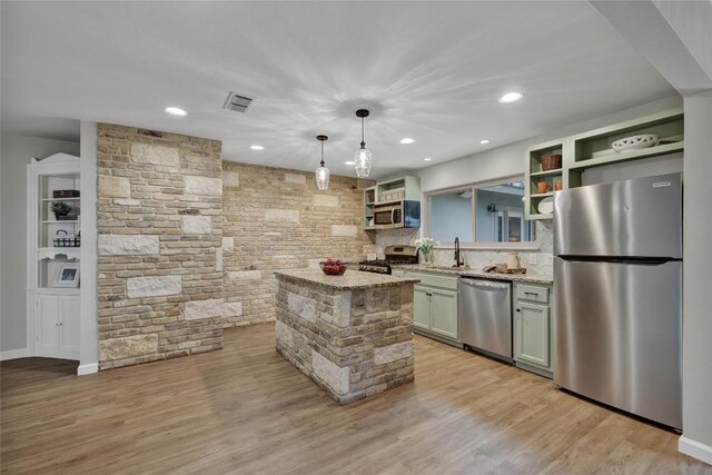 902 W Mill St, New Braunfels, TX 78130 - kitchen featuring appliances with stainless steel finishes, decorative light fixtures, a center island, light stone countertops, and light hardwood / wood-style flooring