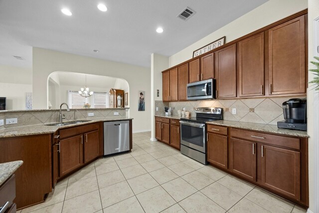 1017 Matheson Dr, Leander, TX 78641 - kitchen featuring appliances with stainless steel finishes, arched walkways, a chandelier, a sink, and backsplash