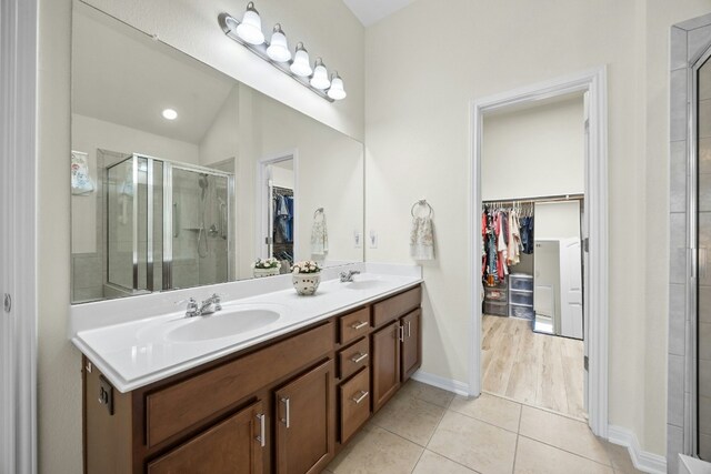 1017 Matheson Dr, Leander, TX 78641 - full bathroom with a spacious closet, double vanity, a stall shower, tile patterned floors, and baseboards