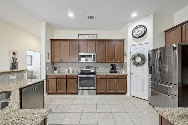 1017 Matheson Dr, Leander, TX 78641 - kitchen with stainless steel appliances, backsplash, light tile patterned floors, light stone countertops, and recessed lighting