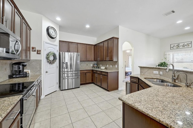 1017 Matheson Dr, Leander, TX 78641 - kitchen with appliances with stainless steel finishes, a sink, decorative backsplash, arched walkways, and light tile patterned floors