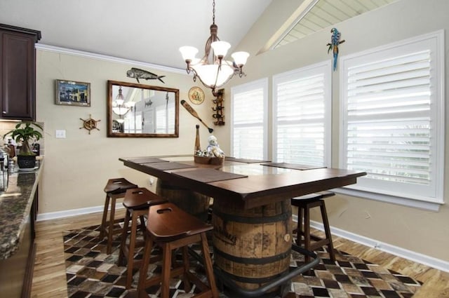 dining room with dark wood-type flooring, an inviting chandelier, and vaulted ceiling