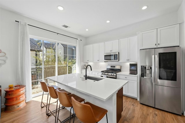 3809 Valley View Rd Unit 19, Austin, TX 78704 - kitchen featuring stainless steel appliances, a sink, an island with sink, backsplash, and a breakfast bar