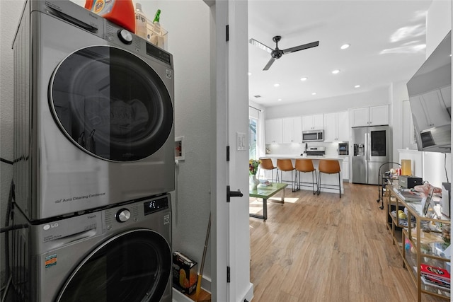 clothes washing area with stacked washer and dryer, ceiling fan, and light wood-type flooring