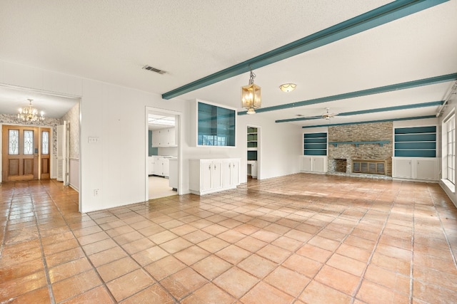 unfurnished living room featuring a textured ceiling, beamed ceiling, built in shelves, and a chandelier