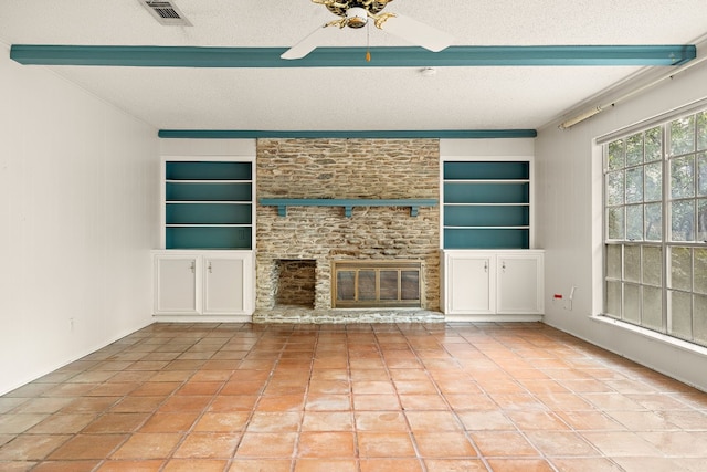 unfurnished living room featuring light tile patterned flooring, a large fireplace, a textured ceiling, beam ceiling, and built in shelves