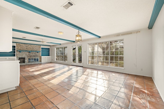 interior space featuring a brick fireplace, beam ceiling, tile patterned floors, and a textured ceiling