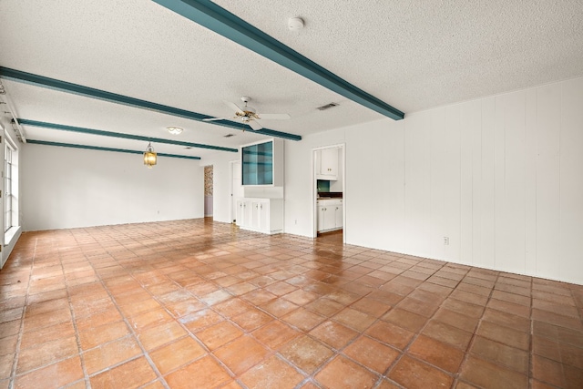 unfurnished living room with ceiling fan, beam ceiling, and a textured ceiling