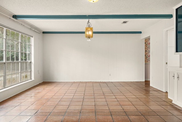 empty room with a textured ceiling and beam ceiling