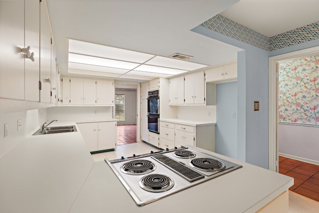 kitchen featuring light tile patterned flooring, white electric cooktop, white cabinetry, sink, and kitchen peninsula