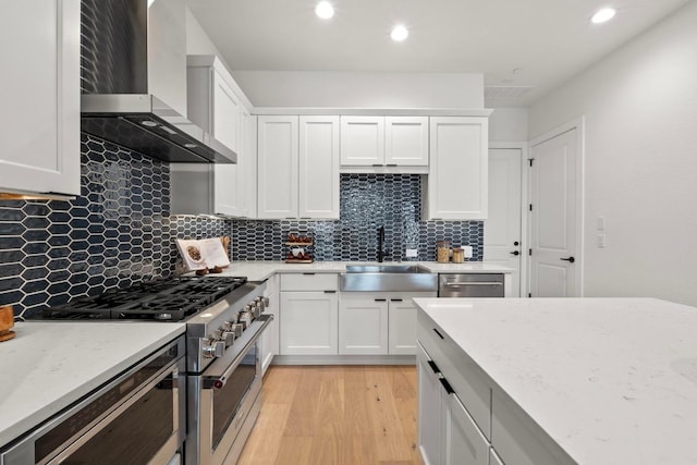 2707 Dulce Ln Unit 7, Austin, TX 78704 - kitchen with wall chimney exhaust hood, appliances with stainless steel finishes, light wood-style flooring, white cabinets, and recessed lighting