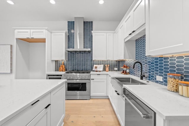 2707 Dulce Ln Unit 7, Austin, TX 78704 - kitchen featuring stainless steel appliances, wall chimney exhaust hood, white cabinetry, recessed lighting, and light wood-type flooring