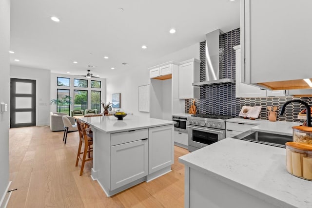 2707 Dulce Ln Unit 7, Austin, TX 78704 - kitchen featuring high end range, wall chimney exhaust hood, light wood finished floors, backsplash, and a ceiling fan