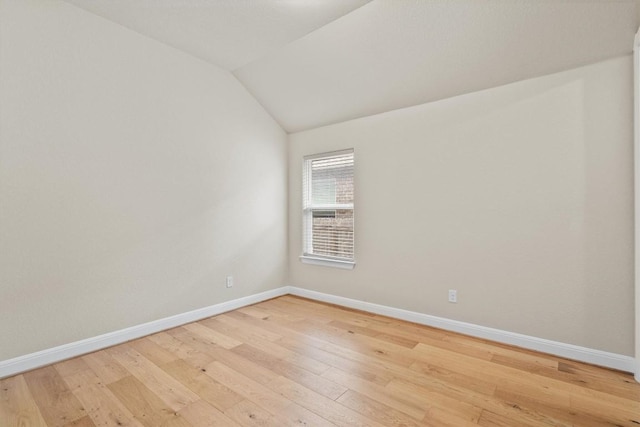 spare room with vaulted ceiling and light wood-type flooring