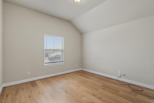 spare room with lofted ceiling and light wood-type flooring