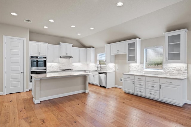 kitchen featuring tasteful backsplash, light hardwood / wood-style flooring, a kitchen island, stainless steel appliances, and white cabinets