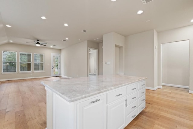 kitchen featuring a kitchen island, ceiling fan, light stone countertops, light hardwood / wood-style floors, and white cabinets