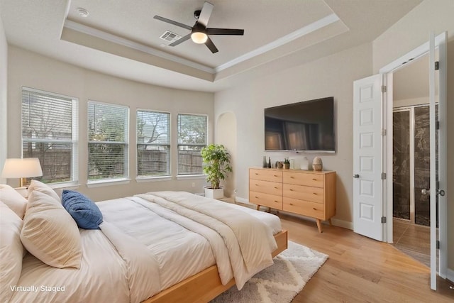 bedroom featuring ornamental molding, a raised ceiling, ceiling fan, and light wood-type flooring