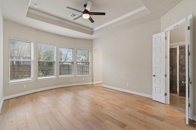 unfurnished room with light hardwood / wood-style flooring, ornamental molding, a raised ceiling, and ceiling fan